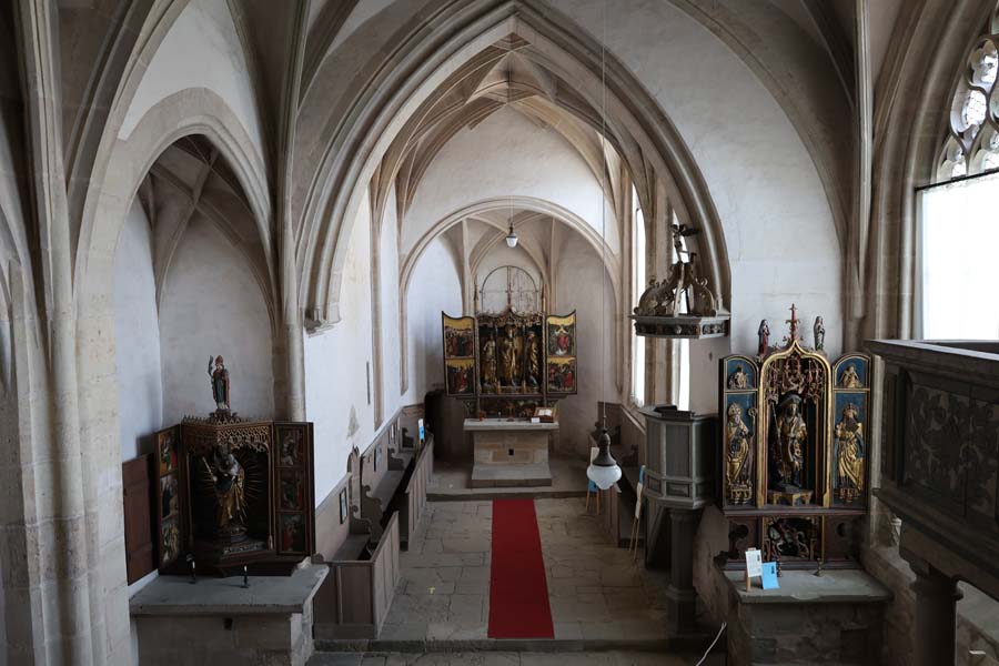 3 altars in the church with brown pulpit, red carpet in the middle